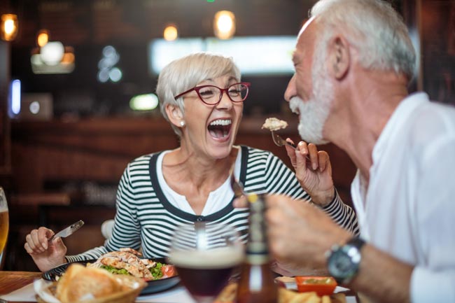 Senior bei der FÃƒÂ¼tterung ihrer mÃƒÂ¤nnlichen Partner im Restaurant lachende Frau Lizenzfreies stock-foto